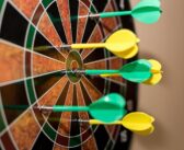 green and yellow darts on brown black green and red dartboard
